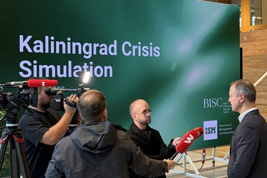 TV crews interview a participant in front of a screen reading Kaliningrad Crisis Simulation, with the BISC and ISM logos.